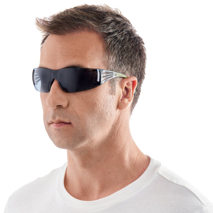 Ein Mann mit kurzen braunen Haaren modelliert die 3M™ SecureFit™ Schutzbrille 400 von 3M Deutschland GmbH. Er trägt eine schwarze Rundum-Schutzbrille und ein weißes T-Shirt vor einem schlichten weißen Hintergrund.