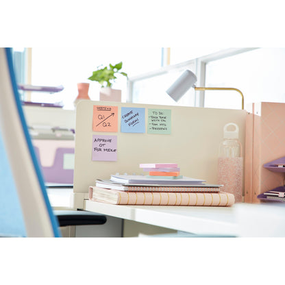 Ein moderner Bürotisch mit Notizbüchern, einer Wasserflasche, einem 3M Deutschland GmbH Post-it® Super Sticky Notes (76 x 127 mm, 90 Blatt, 100% PEFC) auf einer Trennwand, einer Lampe und Ordnern im Hintergrund. Einige Notizen zeigen Erinnerungen und Aufgaben.