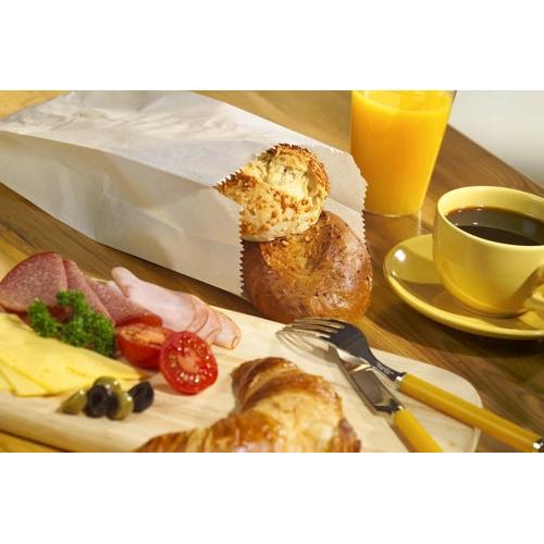 On a wooden table: black coffee, orange juice, and a PAPSTAR 1000 paper folding bag (cellulose, PAPSTAR GmbH) with two rolls, a croissant, and a wooden board with sliced cheese, cold cuts, tomatoes, olives, and parsley.