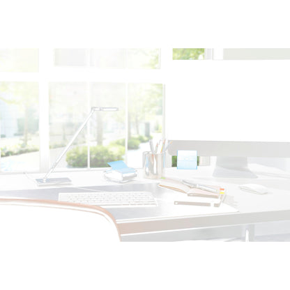 Eine moderne Schreibtischeinrichtung mit einem 3M Post-it® Z-Notes Dispenser PRO in Schwarz mit gelben Post-it® Super Sticky Z-Notes (76x76 mm, 90 Blatt/Block), Notizbüchern, Stiften und einer Lampe vor großen Fenstern mit Sonnenlicht und grünen Bäumen draußen.