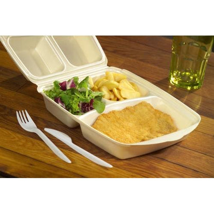 A Starpak 50 menu box with a flip lid, XPS beige laminated, contains a breaded schnitzel, French fries, and green salad. Next to it are a plastic fork and knife; in the background, there is a yellow-green drink in a glass.