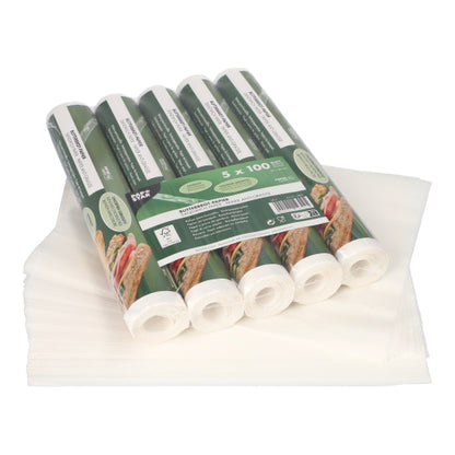 Five packs of PAPSTAR wax paper, each with 500 white sheets in the format 25x30 cm, are stacked on unfolded sheets. The green packaging of PAPSTAR GmbH is adorned with food images and details, making it ideal for versatile food storage.