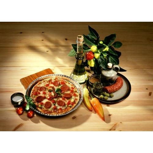 A pepperoni pizza is served on a plate next to wine, salami, olives, and fresh produce. Expertly baked in Starpak 25 round molds, aluminum round by Starpak for optimal heat conduction on a rustic wooden table.