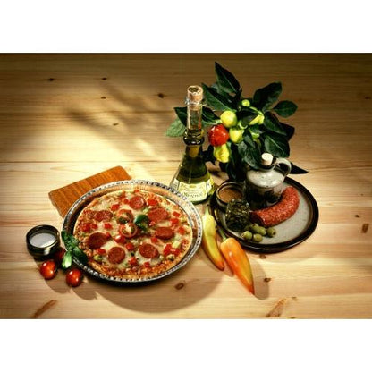 A pepperoni pizza is served on a plate next to wine, salami, olives, and fresh produce. Expertly baked in Starpak 25 round molds, aluminum round by Starpak for optimal heat conduction on a rustic wooden table.