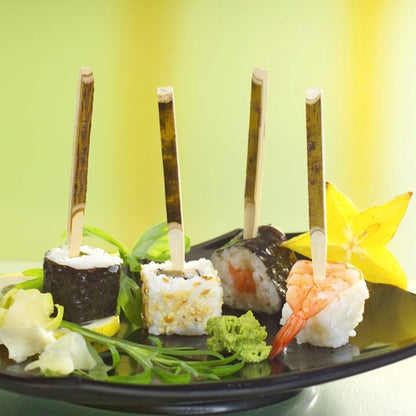 On a PAPSTAR cardboard tray (200 pieces) lie three sushi finger foods on PAPSTAR finger food skewers (11 cm natural wood), accompanied by starfruit, wasabi, ginger, and greens - perfect for parties.