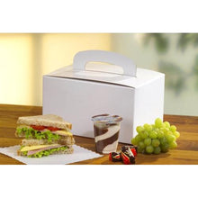 Eine PAPSTAR 20 Lunch-Box aus umweltfreundlicher Pappe (12,5x15,5x22,5 cm) mit Tragegriff von PAPSTAR GmbH steht auf einem Holztisch neben einem Sandwich, Schoko-Vanille-Pudding, zwei Pralinen und grünen Trauben.