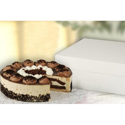 A round cake with layers of chocolate and cream sits on a lace doily next to a closed PAPSTAR 10 cake boxes with lids, white rectangular cardboard from PAPSTAR GmbH; a slice has been cut out, revealing the chocolate and cream inside.