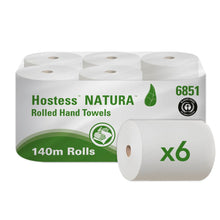 Ein Karton mit sechs Hostess™ NATURA Rollenhandtüchern von Kimberly-Clark GmbH, jede 140 m lange Rolle in Naturfarbe, verfügt über eine umweltfreundliche weiße und grüne Verpackung mit Produktname, Blattlogo und einem Sechs-Rollen-Symbol - ideal für nachhaltige Bedürfnisse.