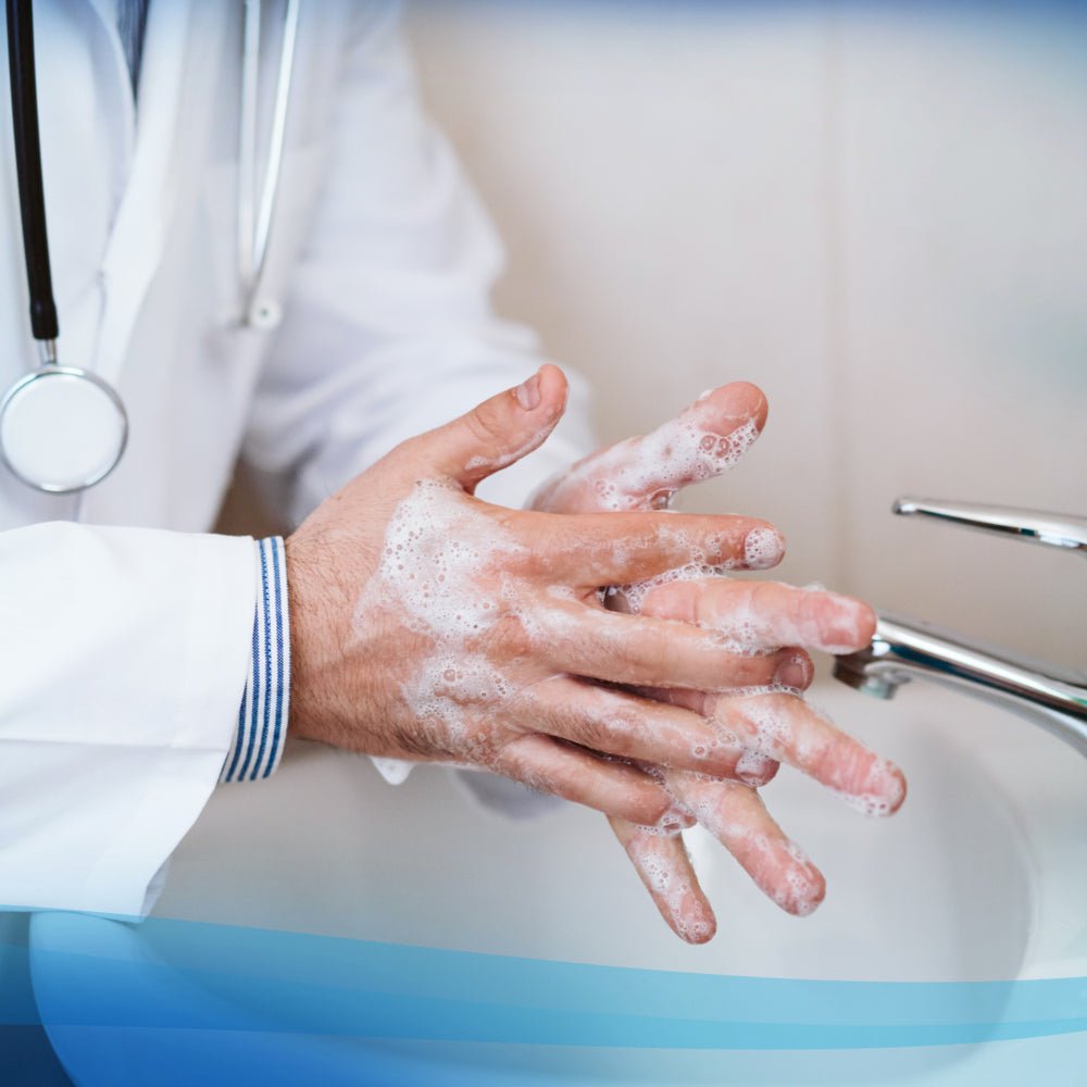 Eine Person in einem weißen Laborkittel benutzt Scott® Control™ Antibakterieller Handreiniger von Kimberly-Clark GmbH an einem Waschbecken und erzeugt Schaum. Ein Stethoskop um ihren Hals unterstreicht die Notwendigkeit einer hygienischen Handreinigung im Gesundheitswesen.