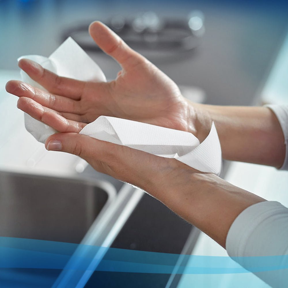 Eine Person benutzt ein weißes Scott® Handtücher - MultiFold Papierhandtuch (Kimberly-Clark GmbH, 16 Clips x 250 Blatt) über einem Waschbecken in einer modernen Küche zum hygienischen Händetrocknen.