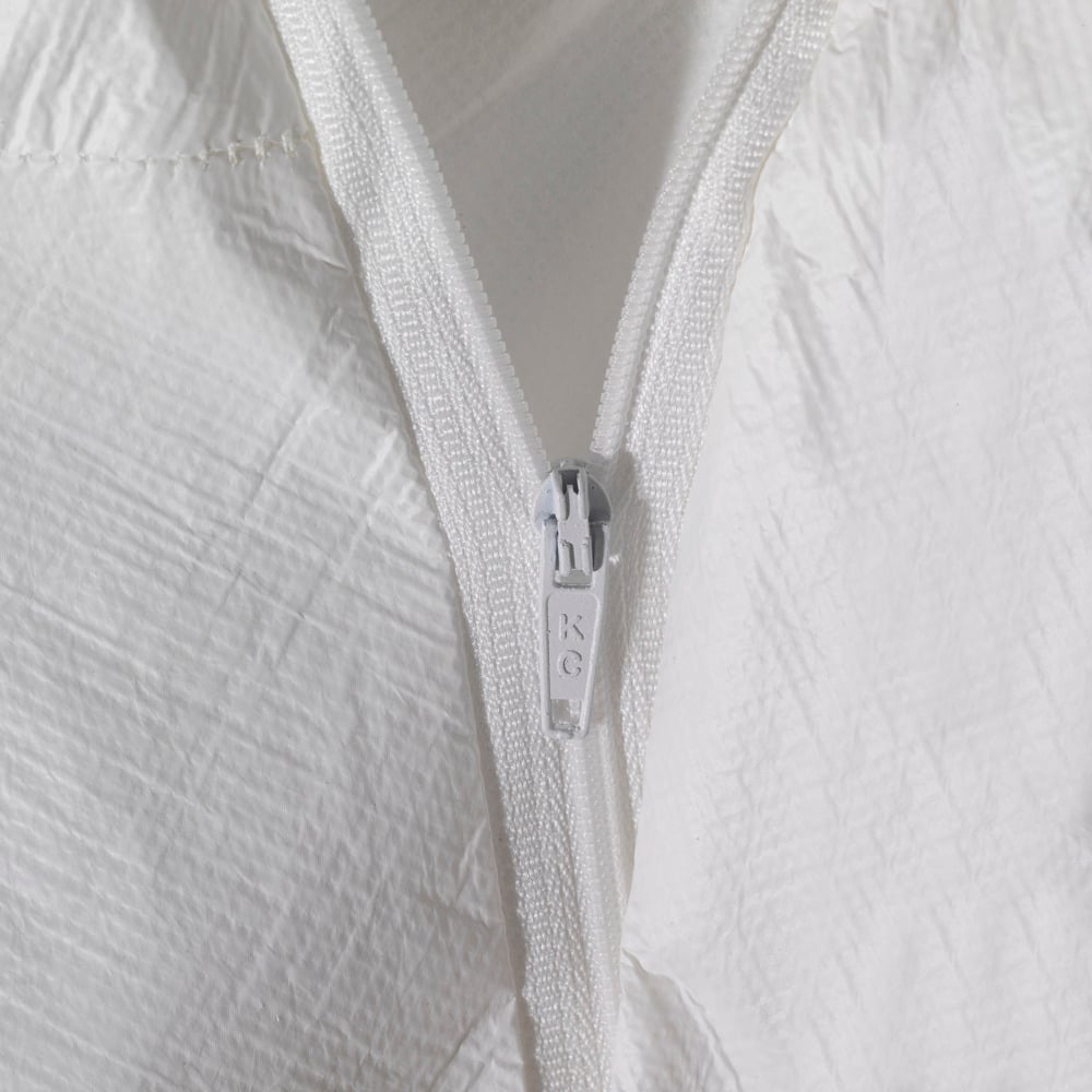 Nahaufnahme eines weißen, teilweise geöffneten Reißverschlusses auf weißem, strukturiertem Stoff, wahrscheinlich von der Kimberly-Clark GmbH KleenGuard® A40 Schutzanzug gegen Flüssigkeiten und Partikel mit Kapuze in Weiß. Auf dem Reißverschlusszug sind die Buchstaben "RC.