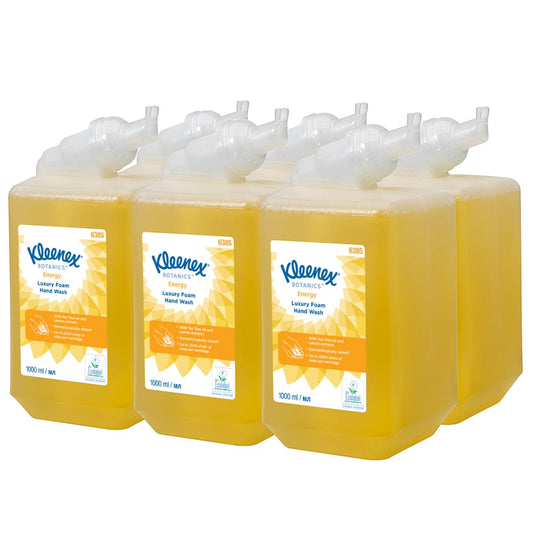 Sechs gelbe 1-Liter-Kassetten Kleenex® Botanics™ Luxury Foam Hand Wash der Kimberly-Clark GmbH sind in zwei Reihen angeordnet, jede mit einer weißen Pumpe und einem orange-weißen Etikett mit Branding und Produktinformation.