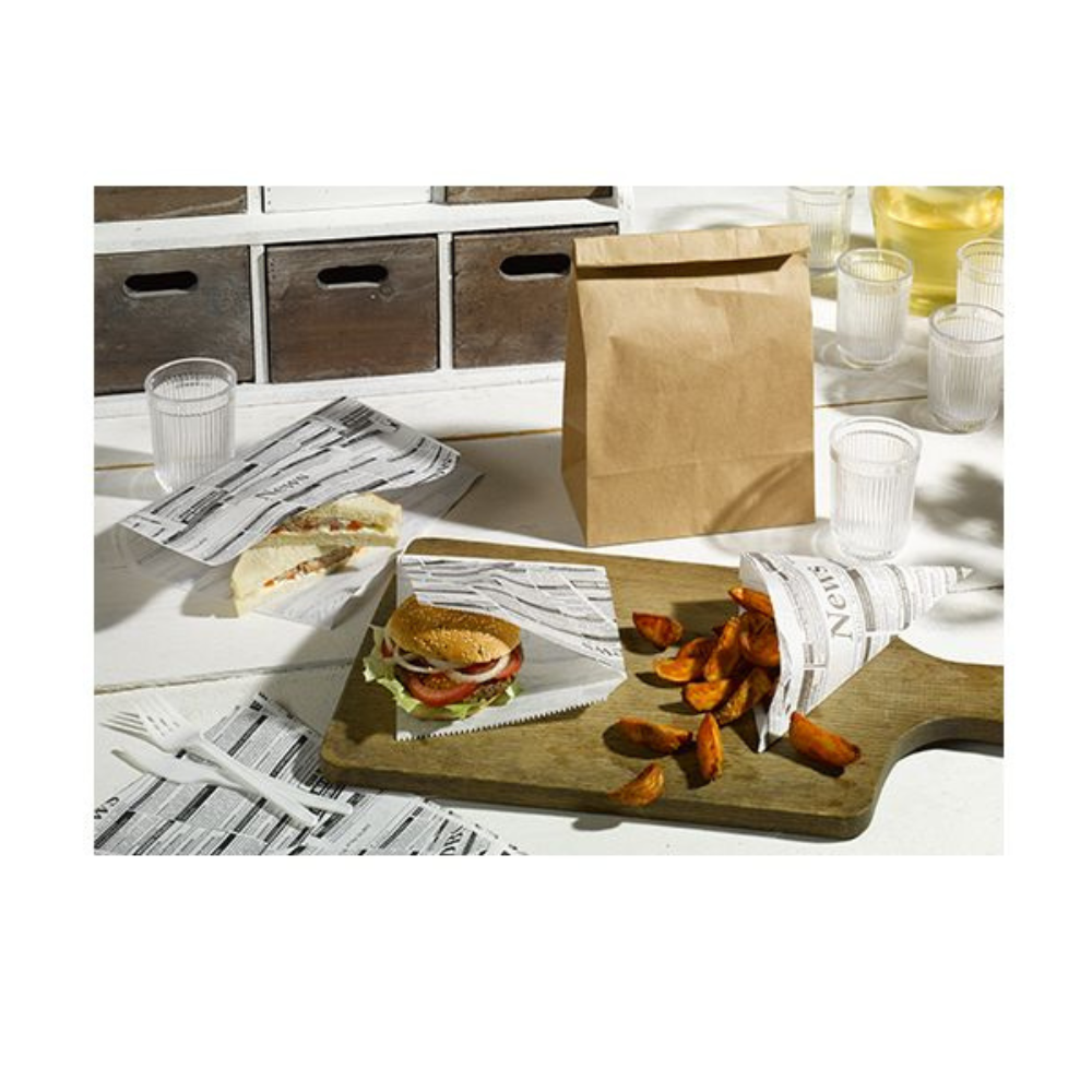 A sandwich and potato wedges are served on a wooden board, using PAPSTAR GmbH hamburger bags "Newsprint", greaseproof, 16x18 cm (pack of 300) as a parchment substitute, with disposable cutlery, napkins, water glasses, and a brown paper bag.