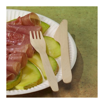 A white paper plate with green apple slices and prosciutto, next to PAPSTAR wooden forks "pure" 16.5 cm - eco-friendly and sturdy (100 pieces) - from PAPSTAR GmbH, along with a wooden knife, on a green background.