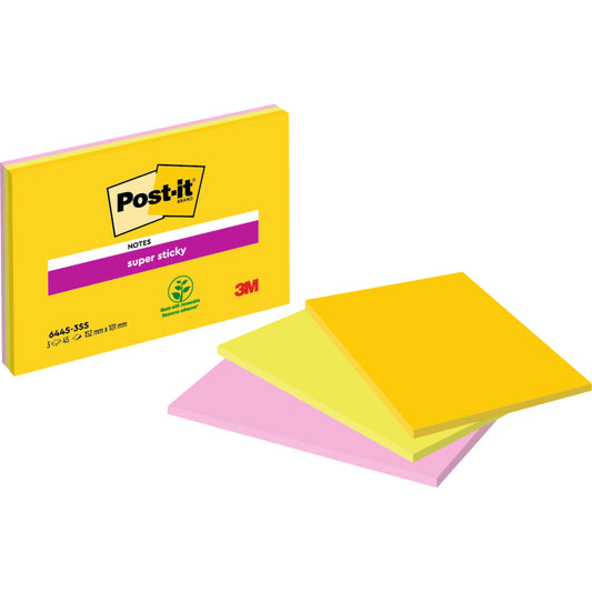 Eine Packung Post-it® Super Sticky Notes im Großformat von 3M Deutschland GmbH liegt neben drei Stapeln gelber und pinker Haftnotizen. Die Verpackung zeigt das 3M-Logo, ein Symbol für pflanzenbasierten Klebstoff und 100% PEFC.