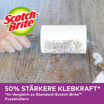Eine Hand benutzt die Scotch-Brite™ Pet Extra Sticky* Ersatzrolle für Tierhaare (48 Blatt, 1/Packung) von 3M Deutschland GmbH, um verschütteten Glitter von Holz zu entfernen. Ein offener Glitterbehälter ist in der Nähe. "50% stärkere Klebekraft" im Vergleich zu den unten abgebildeten Standardrollen.