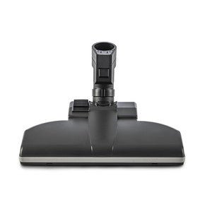 Die TASKI Aero UP Standarddüse von Diversey Deutschland GmbH & Co. OHG ist ein schwarzer Bodenaufsatz mit rechteckiger Basis und zentralem Anschluss, perfekt für gewerbliche Bereiche. Passend für den TASKI Aero UP, Packung (1 Stück), abgebildet Frontansicht auf weißem Hintergrund.