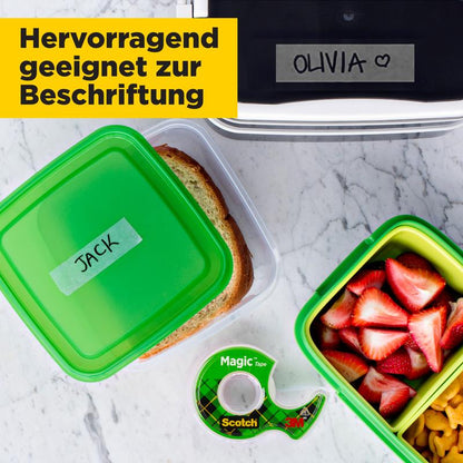 A lunchbox labeled "JACK" and a snack box stand next to a lunchbox labeled "OLIVIA" with a heart. Nearby is a Scotch® Magic™ Invisible Tape, 19 mm x 25 mm by 3M Deutschland GmbH, ideal for labeling.