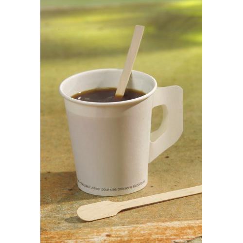 A white disposable cup with dark coffee holds a PAPSTAR stirring stick wood "pure" (13 cm), next to another environmentally friendly wooden stirring stick from PAPSTAR GmbH. The background is gently blurred.