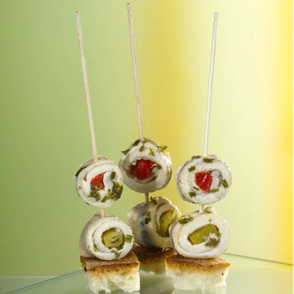 Three rolled fish fillet skewers stand upright on bread cubes, presented as PAPSTAR finger food picks "pure" 15 cm (turned, elegant) from PAPSTAR GmbH - ideal for stylish catering events.