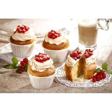 Vier Muffins in weißen PAPSTAR Muffins-Backförmchen Ø 5 cm, 3,2 cm hoch (Folie) von PAPSTAR GmbH sind mit weißem Zuckerguss und roten Beeren auf Stein belegt. Ein Muffins-Backförmchen ist halbiert, um das Innere zu zeigen; Minze und Kaffee erscheinen im Hintergrund.