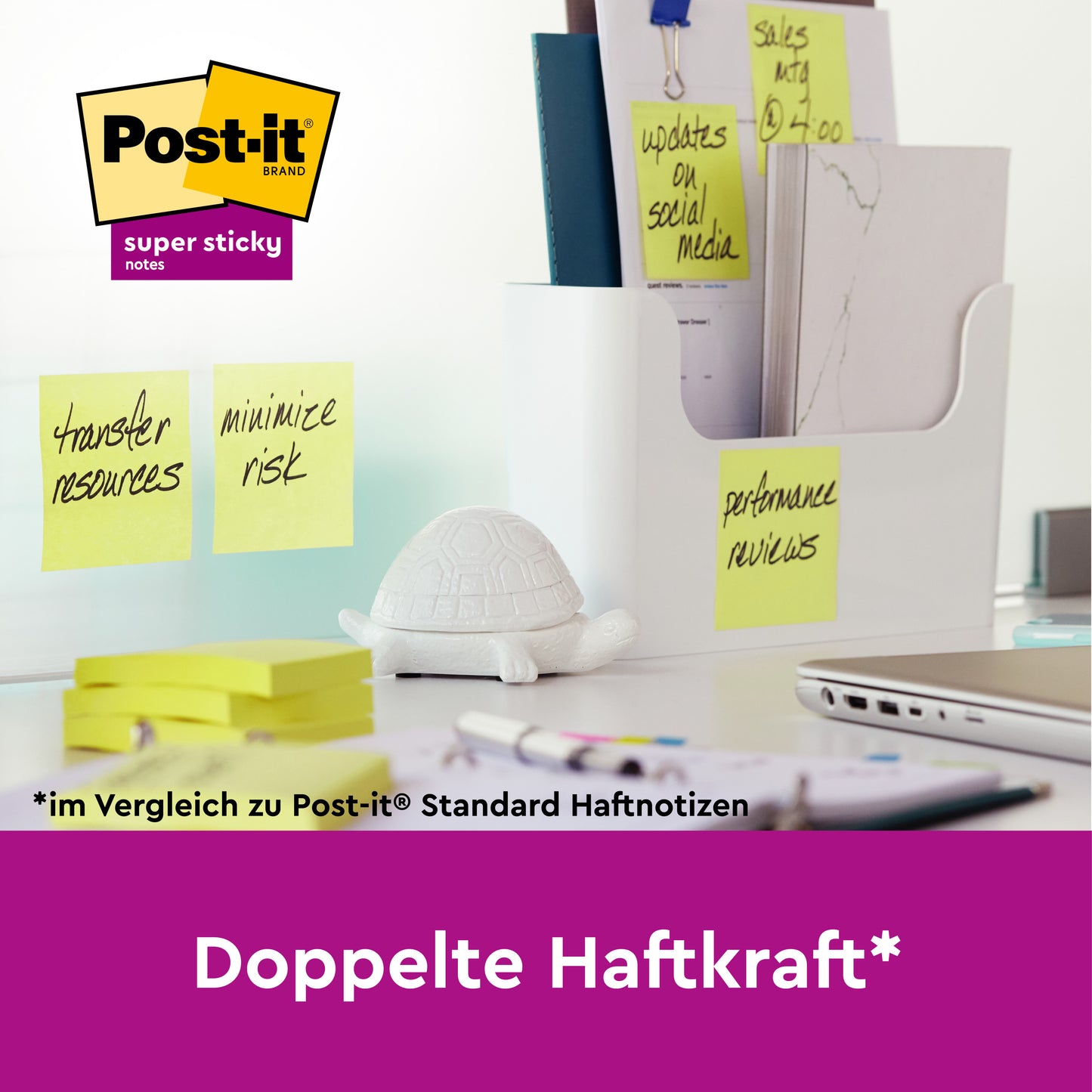 Auf einem Schreibtisch liegen 3M Post-it® Super Sticky Z-Notes in Gelb (76x127mm, 90 Blatt, 12 Blöcke, PEFC-zertifiziert) auf Glas neben einer weißen Trennwand mit Büromaterialien, einer Schildkrötenfigur und dem Schriftzug "Doppelte Haftkraft*".