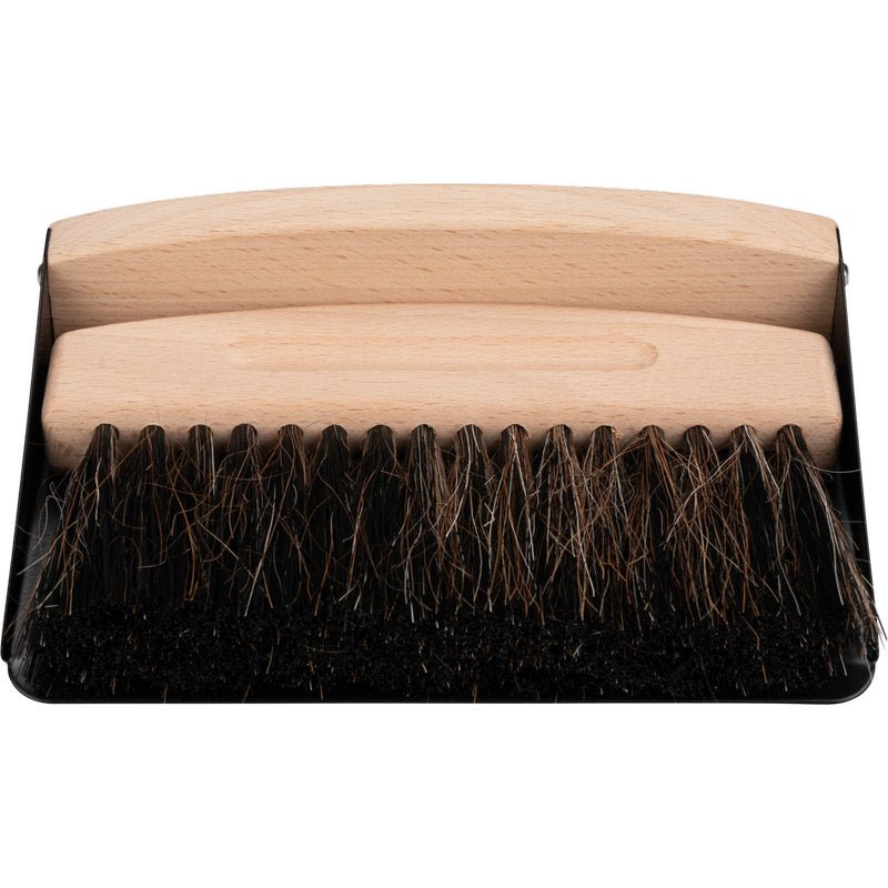 A hand brush with a wooden handle and dark bristles sits on a black dustpan - ideal like the ENA Living table sweeping set from Abena Re-Seller GmbH (24-pack) for easy table cleaning.