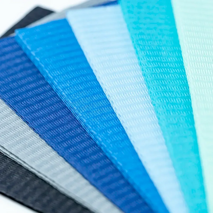 A fan-like arrangement of fabric samples in various shades of blue, reminiscent of AMPri Dental disposable patient napkins used in dental procedures. The colors range from dark to light. The fabrics feature a textured pattern, with each pattern slightly overlapping the next.
