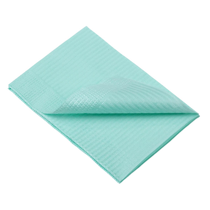 A folded, light blue AMPri Dental disposable patient napkin with a textured surface lies flat against a white background. The edges are neatly aligned, and one corner is turned over, making both sides visible.