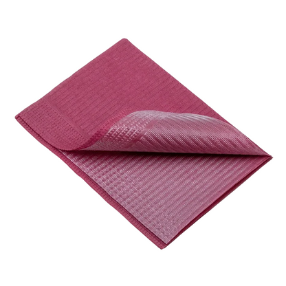 A folded AMPri Dental disposable patient napkin in a pink hue, similar to those used in dental treatment, is presented against a white background, highlighting its textured surface.