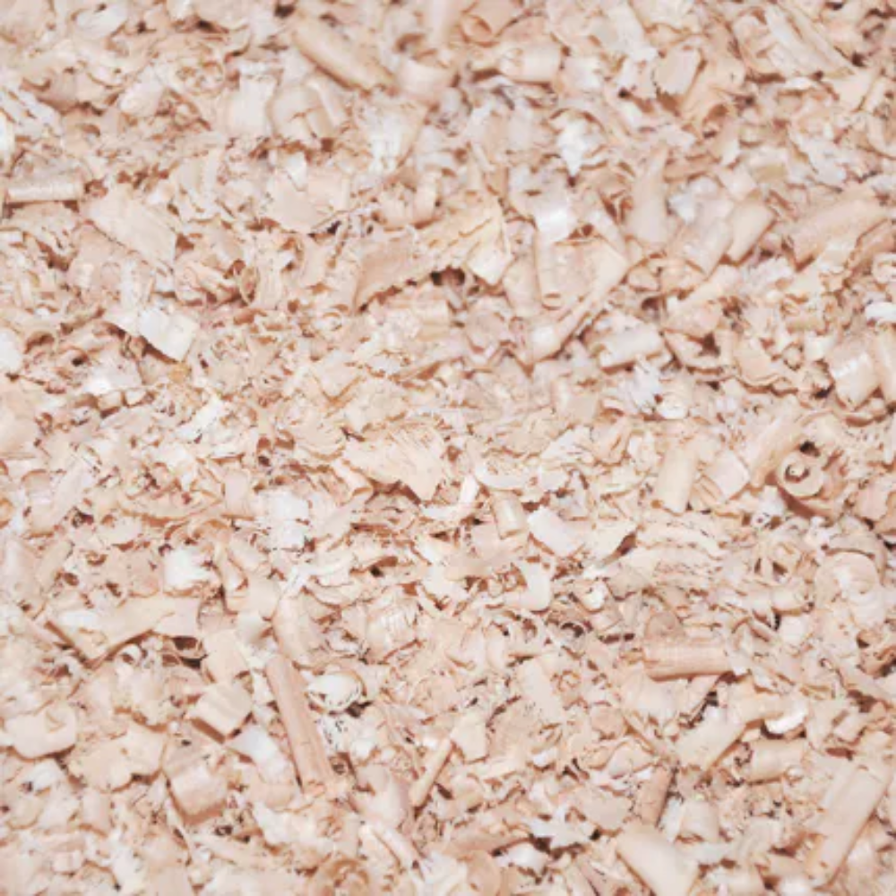 A close-up shows Allspan German Horse Classic wood shavings bedding densely scattered, with shavings of different sizes and shapes forming a textured surface. The shavings have a high level of dryness and a beige to light brown color, typical of freshly planed wood.