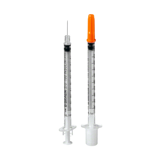 Zwei B. Braun Omnican® 100 Einmal-Insulinspritze mit nummerierten Messmarkierungen; eine mit aufgesetzter Nadel und orangefarbener Kappe, die andere ohne Nadel und mit weißer Kappe, aufrecht stehend.