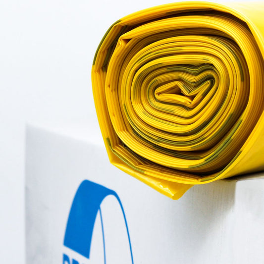 Eine Nahaufnahme eines sauber gerollten DEISS Premium® Infektions-Wäschesacks 93008, 85 Liter in Gelb mit scharfer Kante, positioniert vor einem weißen Hintergrund mit einer Teilansicht eines blauen Architekturplan-Logos.