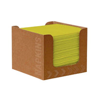 A brown cardboard dispenser contains a stack of green Duni Bio-Dunisoft napkins (Kiwi, 20 x 20 cm) from Duni GmbH, with the word “SERVIETTEN” and arrows printed on the side. The biodegradable napkins are visible and neatly arranged through the open sides.