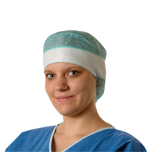 Eine junge Ärztin trägt einen blauen OP-Kittel und eine Hartmann Foliodress® Cap Comfort Form Plus OP-Hauben Einweghaube aus atmungsaktivem Viskose-Vliesstoff und lächelt sanft in die Kamera. Der Hintergrund ist schlicht weiß.