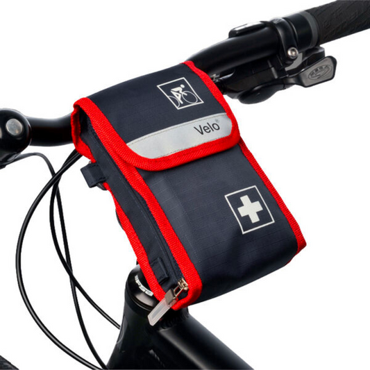 Eine rot-schwarze Holthaus Medical Velo® Fahrradverbandtasche, die am Lenker eines Fahrrads befestigt wird und auf deren Oberfläche deutlich sichtbar ein weißes Kreuzsymbol und das Logo „Vélo“ zu sehen sind.