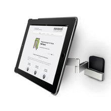 Eine Novocal Tablethalterung Variante 1 (für Tablets 7-12 Zoll, schwenkbar bis 180°) ist an einer silbernen Wandhalterung mit Schwenkarm montiert; auf dem Tablet ist eine Website mit "novocal" als Überschrift zu sehen.
