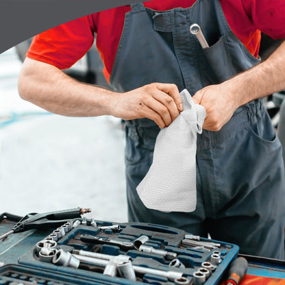 A person in a red shirt and gray overalls uses a WypAll® X70 PowerClean cloth from the BRAG™ Box of Kimberly-Clark GmbH next to an open toolbox to highlight the efficient industrial cleaning with 200 white towels per box.