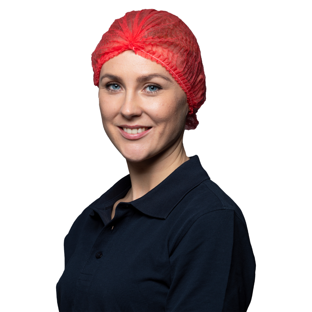 Eine Frau mit dunkelblauem Shirt und rotem NITRAS Klipphauben Haarnetz der MCD MEDICAL CARE DENTAL GmbH lächelt vor weißem Hintergrund sanft in die Kamera.