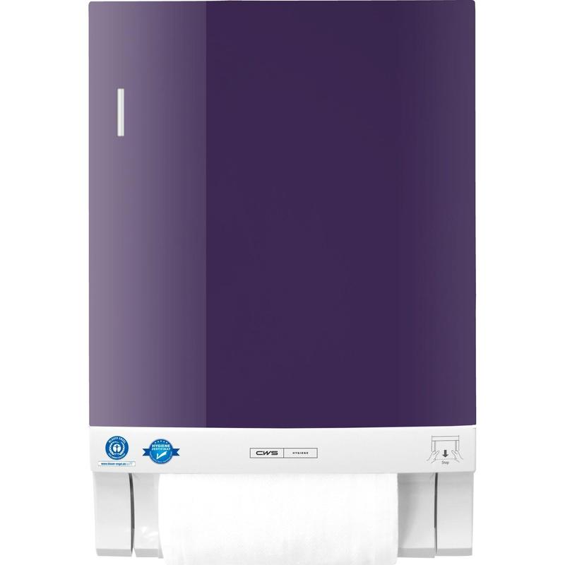 Ein wandmontiertes CWS Frontpanel für Stoffhandtuchspender Dry Slim in Lila mit weißem Sockel zeigt eine sichtbare Papierhandtuchrolle an der Unterseite. In der linken unteren Ecke befinden sich zwei blaue Zertifizierungsaufkleber. Marke: CWS.