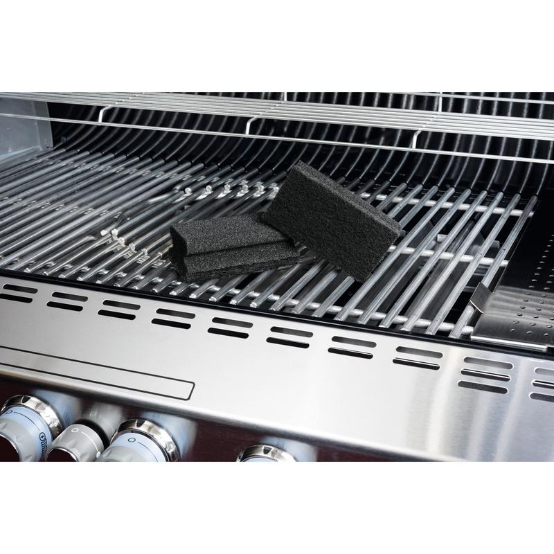 Ein Scotch-Brite® Grill Griffschwamm von 3M Deutschland GmbH liegt auf einem Edelstahl-Grill und betont die einfache Grillreinigung. Auf dem Rost sind die schwarzen Schwämme, Grillknöpfe und der geöffnete Deckel sichtbar.