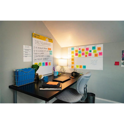 A home office with a black desk, gray chair, lamp, notebooks, a pen holder, and two Post-it® Easy Erase Whiteboard Surfaces from 3M Deutschland GmbH, covered with notes. Colorful sticky notes and a to-do list adorn the wall.