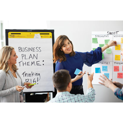 Während einer Geschäftsbesprechung bei der 3M Deutschland GmbH zeigt eine Frau auf eine SWOT-Analyse, während eine andere einen Marker neben ein Flipchart mit der Aufschrift "Business Plan Theme" hält: Thinking BIG!" mit Post-it® Super Sticky Notes, 76 mm x 127 mm, 90 Blatt/Block, 100% PEFC.