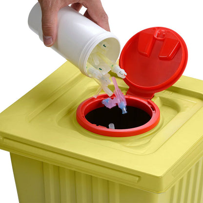 Eine Hand entsorgt gebrauchte Spritzenspitzen aus einem weißen Helmut Schwarz GmbH melijekt Entsorgungsbehälter 12 L in einen gelben Medizinabfallbehälter mit rotem Deckel und stellt so die ordnungsgemäße Entsorgung sicher.