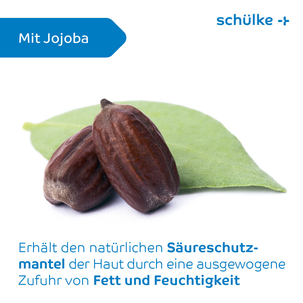 Two jojoba seeds rest on a green leaf against a white background. The image contains German text describing the benefits of Schülke sensiva® protective emulsion for maintaining the skin's acid mantle with balanced fat and moisture supply, similar to the fragrance-free protective lotion. The brand name “Schülke & Mayr GmbH” appears in blue.